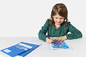 Kind schreibt in Basisline-Heft
